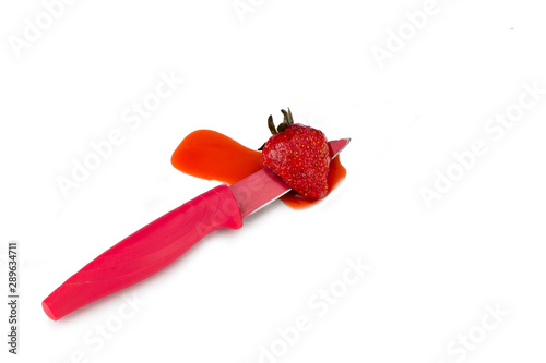 Strawberry pierced by knife, spilling strawberry juice.