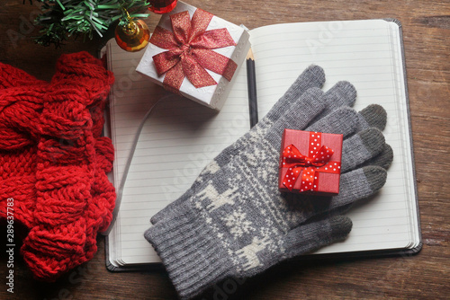 Blank planing book with pencial on the table decorate with christmas tree and red gift box on winter gloves and red yarn hats photo