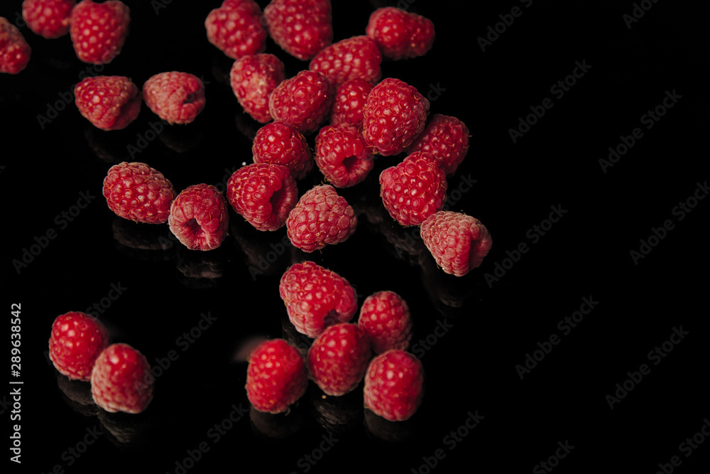 berries of red raspberries in a bunch lie isolated on a black background top view. sweet summer berries berries of red raspberries in a bunch lie isolated on a black background top view. sweet summer berries