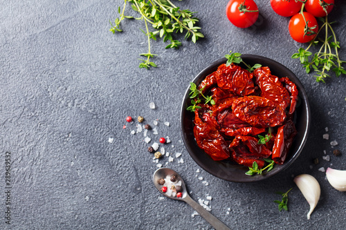 Sun dried tomatoes with fresh herbs and spices. Slate background. Top view. Copy space. photo