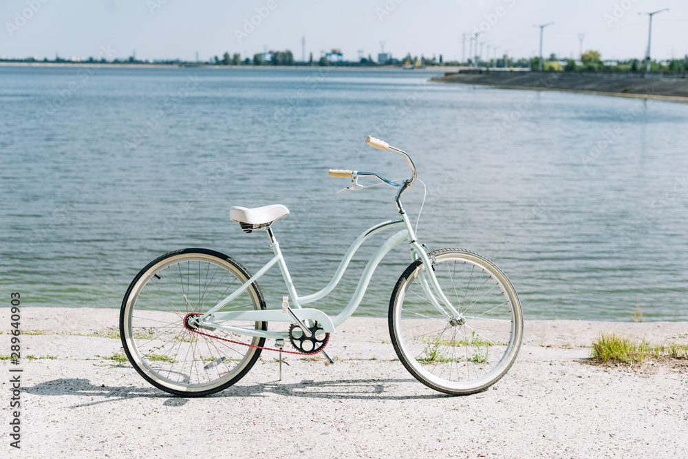 Fototapeta premium side view of bicycle near blue river in summer in sunshine