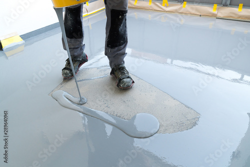 construction worker renovates balcony floor and pours watertight resin and glue before chipping and sealing