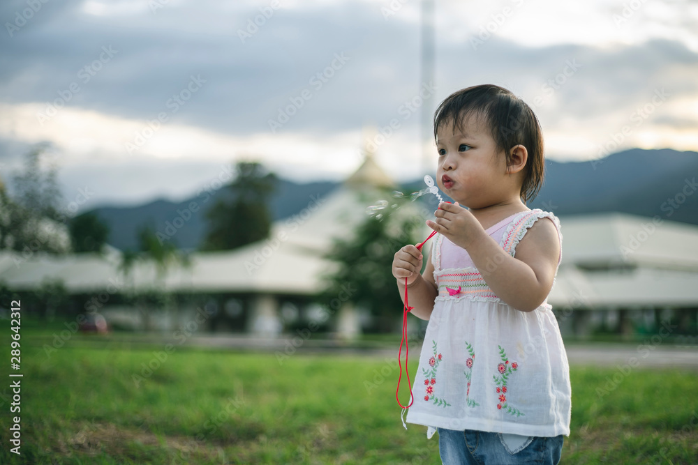 Little child girl playing with bubbles on green grass outdoors in the park. Little child girl playing with bubbles on green grass outdoors in the park.