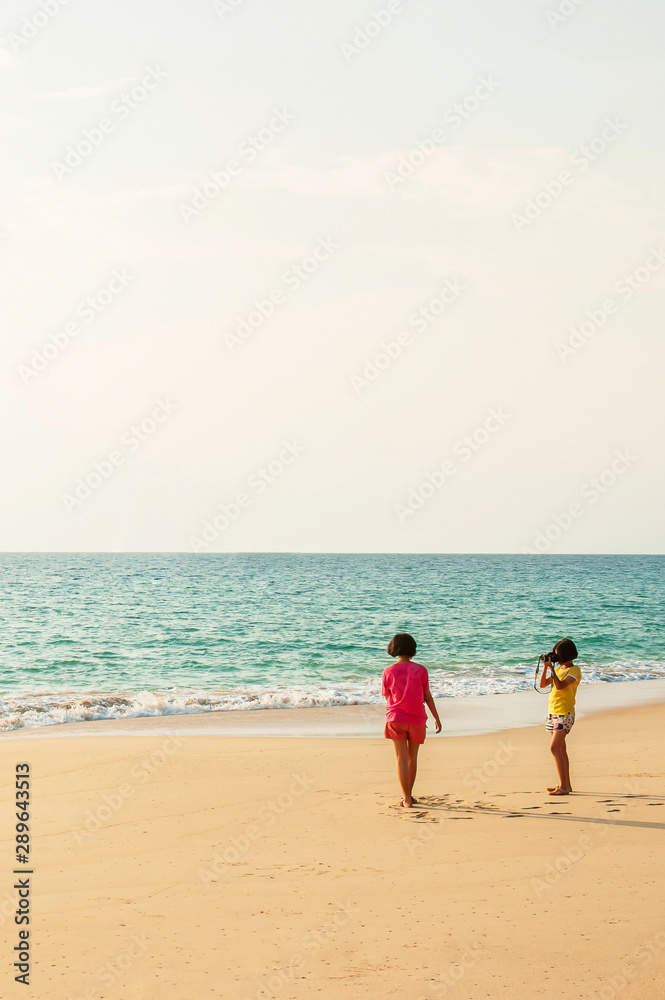 Two girls relaxing on the beach with digital camera.