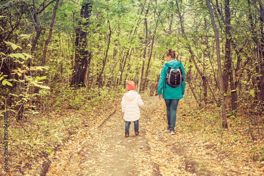 Mother and daughter are walking in the autumn forest