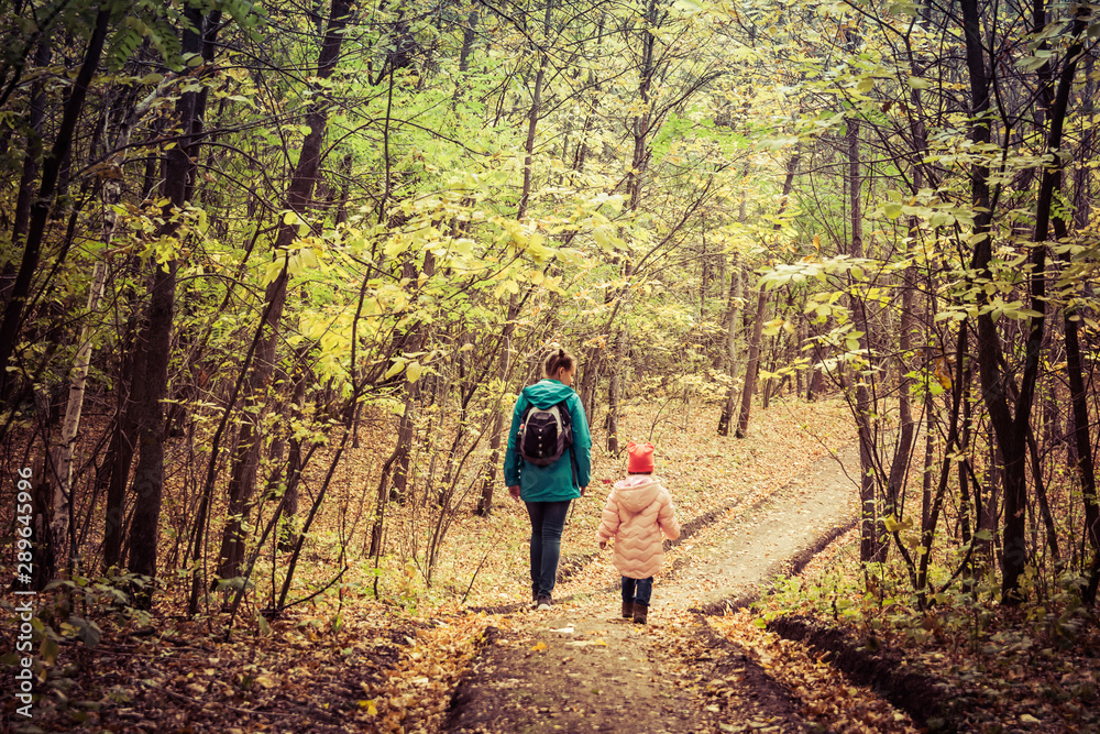 Fototapeta premium Mother and daughter are walking in the autumn forest