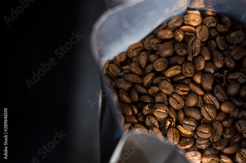 Obraz na płótnie Lots of coffee beans in a bag on dark background. Arabica. Coffee shop. w salonie
