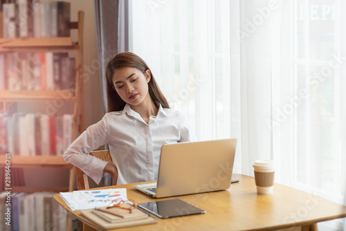 Businesswoman feeling pain in spine back after sedentary computer work sitting in bad posture in office