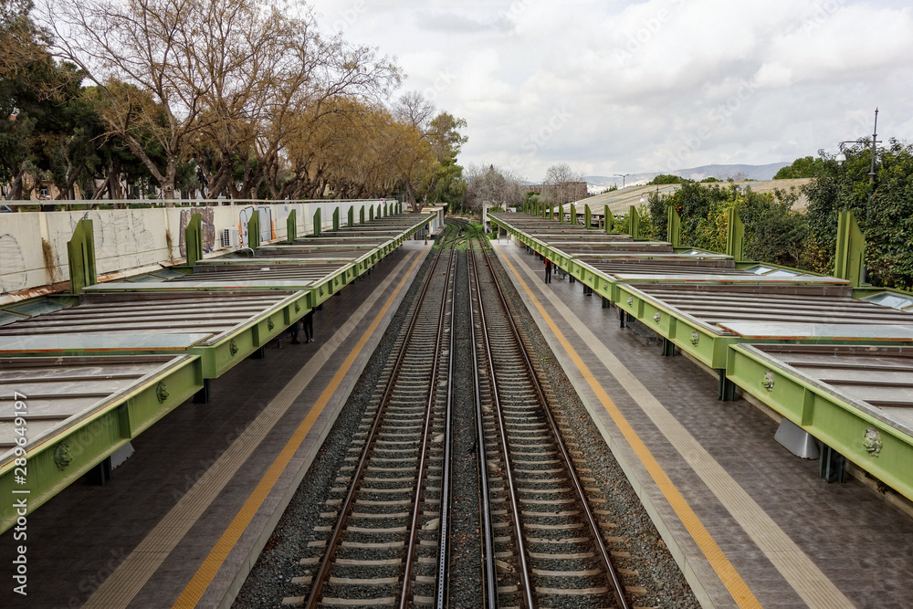Outdoor metro train station in Athens, Greece with two rails and strong perspective view