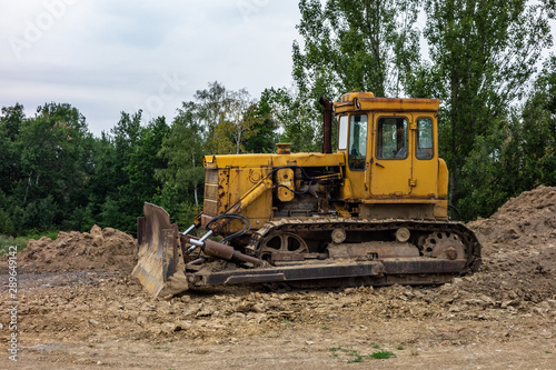 A yellow bulldozer on a constrction site preparing a terrain in order to build a new building