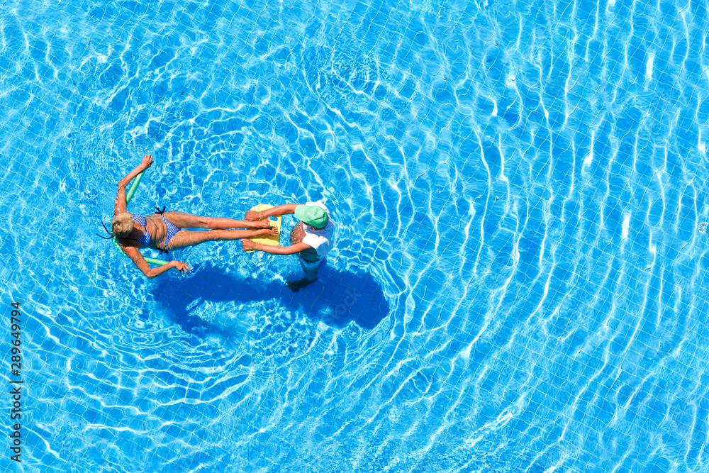 Man and woman in outdoor swimming pool, top view.