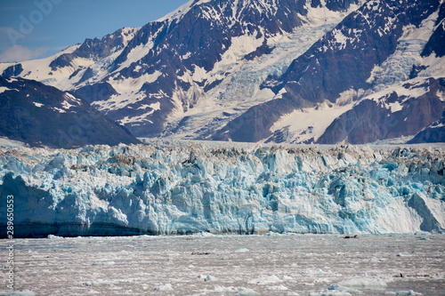 Glacier in Alaska with bright blues and huge mountains behind. 
