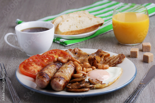 Classic English breakfast served: eggs, bacon, beans, juice and tea 