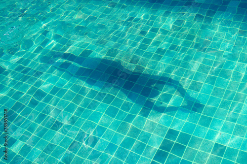 Women's shadow on the water in the pool, top view.