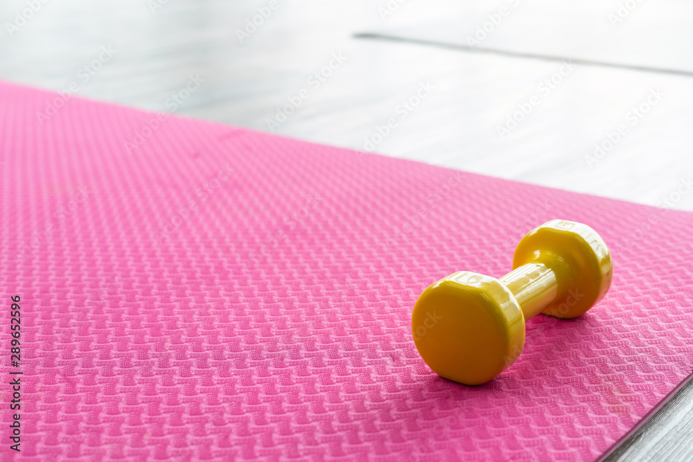 yellow dumbbells on an empty pink rubber floor on wooden floor background,top view with copy space health and exercise concept