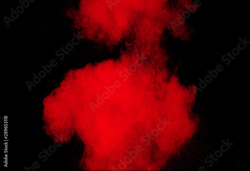 Red powder explosion cloud on black background. Freeze motion of red color dust particles splashing.