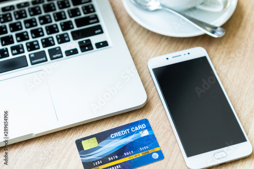 Credit card of laptop computer,smartphone and coffee cup on wooden background, Online banking Concept