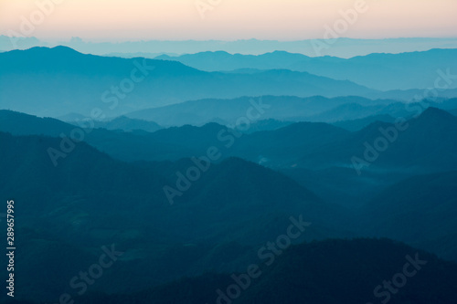 Panoramic view of mountain layer landscape in morning sun ray and winter fog.