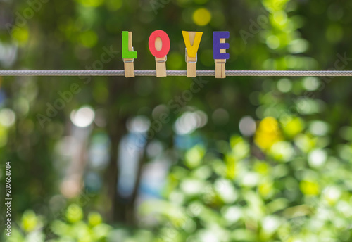 LOVE alphabet hang on sling with beautiful blurred bokeh background of green leaf