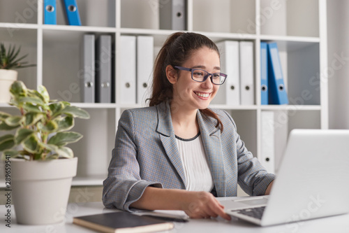 Cheerful intern browsing laptop in office