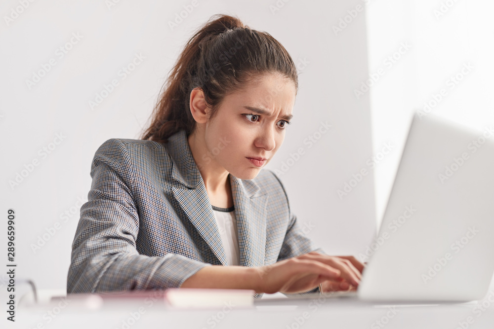 Strained trainee using laptop in office Strained trainee using laptop in office