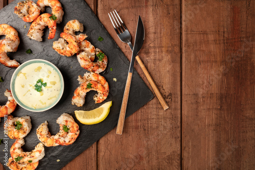 Fried shrimps with a Caesar sauce and lemon, shot from the top on a dark rustic wooden background with a place for text