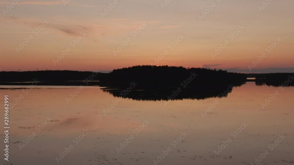 Sunset. Drone shot of landscape with lake and island. Golden sky and horizon. Sun, sky and clouds reflection in water. Wild nature. Sunset. Drone shot of landscape with lake and island. Golden sky and horizon. Sun, sky and clouds reflection in water. Wild nature.