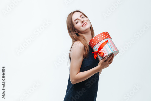 The girl received a gift box and is happy on a light background