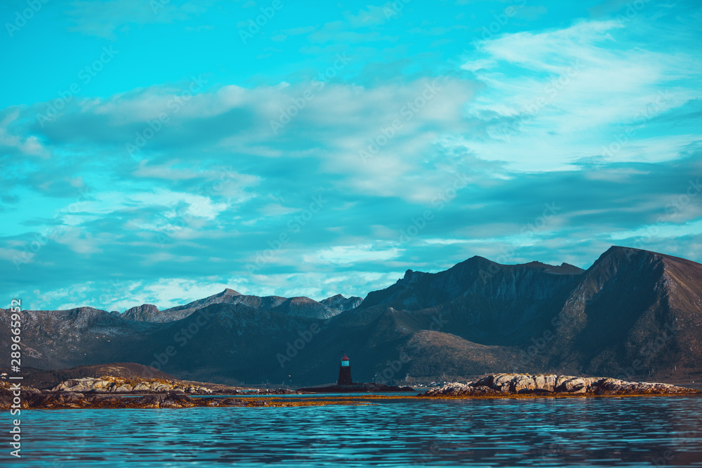 Photo of lighthouse, hills, sea, sky in Norway on summer.