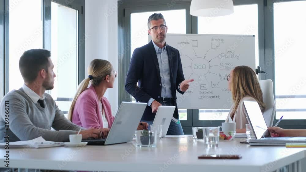 Video of handsome businessman explaining a project to his colleagues on coworking place.