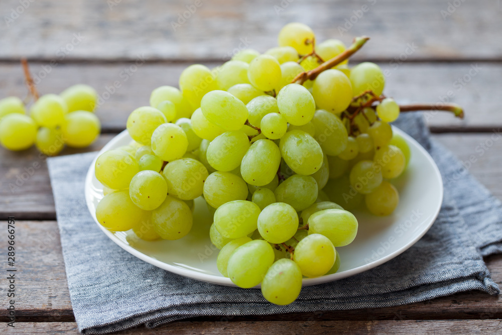 Grape on a white plate. Grey wooden background. Close up. Grape on a white plate. Grey wooden background. Close up.