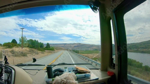 POV of the passenger in a Recreational Vehicle RV while driving through the Scablands of east central Washington State; with the Columbia River to the right and a labradoodle dog in the foreground photo