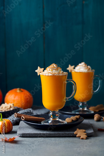 Pumpkin latte with spices. Boozy cocktail with whipped cream on slate board. Grey and blue background. Copy space.