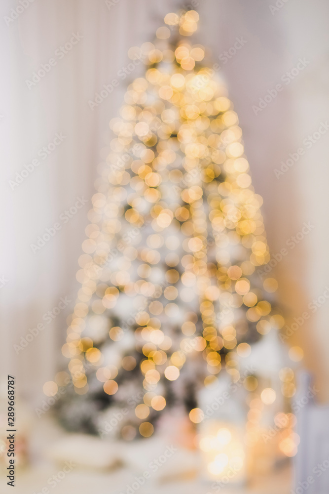 Blurry beautiful Christmas tree standing in livingroom. Vertical color photography.