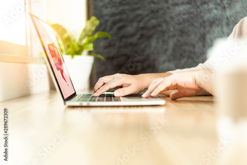 Woman using laptop computer shopping online on wood table near the window at home.Online shopping concept.