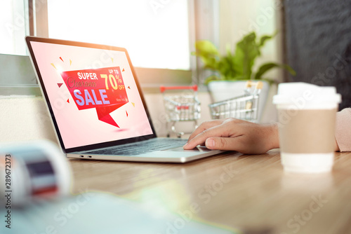 Woman using laptop computer shopping online on wood table near the window at home.Online shopping concept.