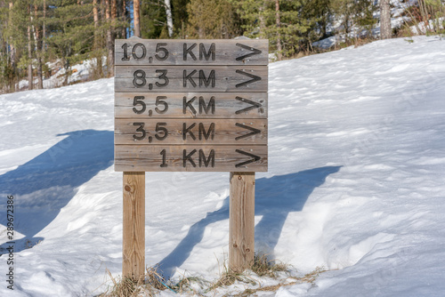 Bilde på lerret wooden pointer with arrow and distance in kilometer in winter park for recreatio