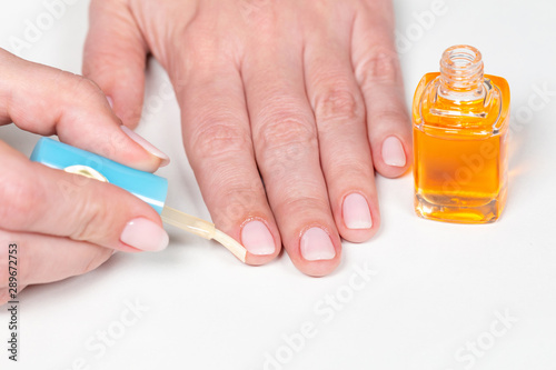 Closeup view of white woman applying cuticle oil to skin after manicure. Horizontal color photography.