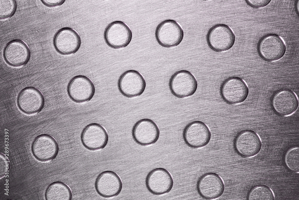 Closeup view of grey stainless metal texture with round circles pattern. Horizontal color photography.