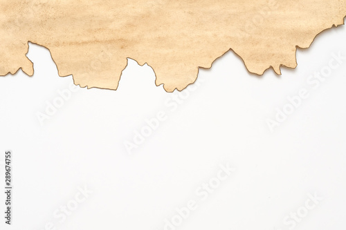 Cropped shot of old stained beige paper with burnt edge on white background. Vintage texture abstract design. Copy space.