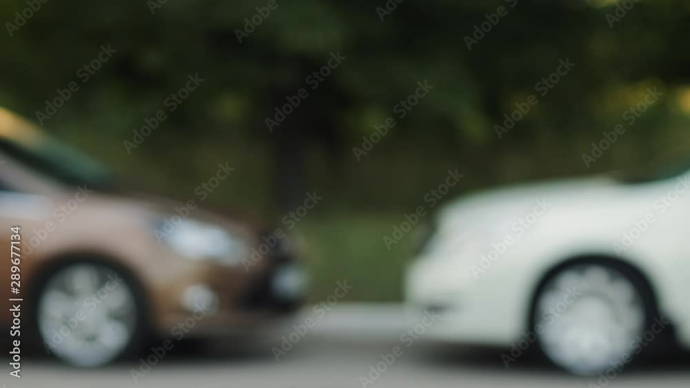 Man hands keys to another person, close-up of hands on a blurred background of cars Man hands keys to another person, close-up of hands on a blurred background of cars