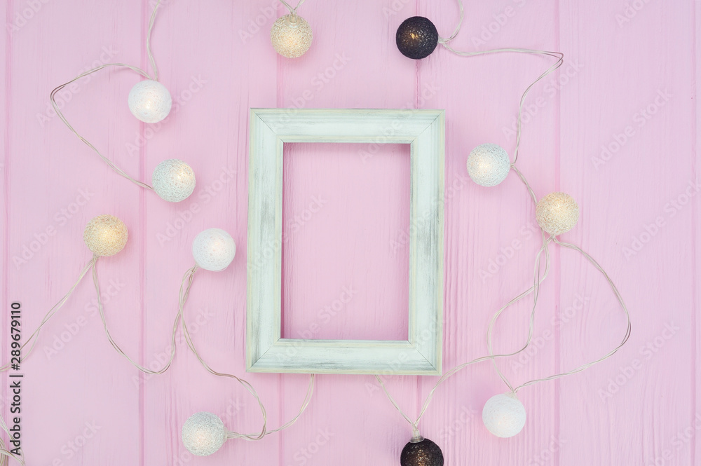 white wooden frame mockup with place for text. Garland on pink wooden background in scandinavian style. for artwork, prints or photo white wooden frame mockup with place for text. Garland on pink wooden background in scandinavian style. for artwork, prints or photo