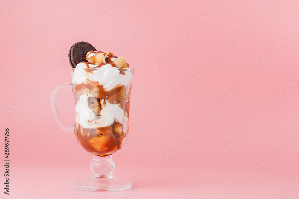 Sweet dessert in glass with biscuit and whipped cream on pink bsckground, selective focus and blank space Sweet dessert in glass with biscuit and whipped cream on pink bsckground, selective focus and blank space