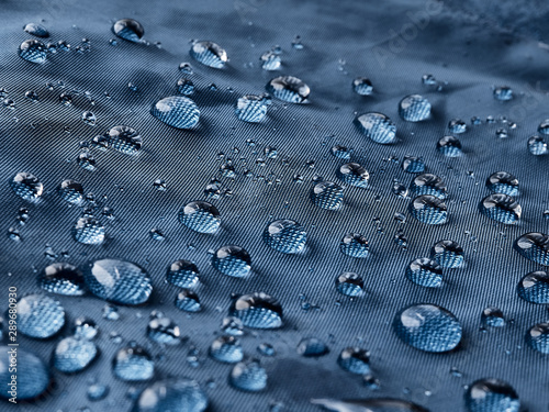 Rain water droplets on blue fiber waterproof fabric. Blue background. photo