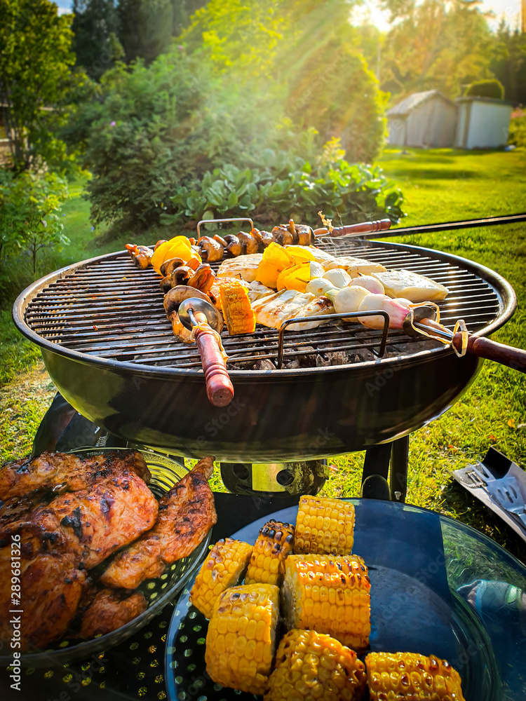 Assorted delicious grilled meat and vegetables over coal barbecue grill in  sunny green garden. Stock Photo | Adobe Stock