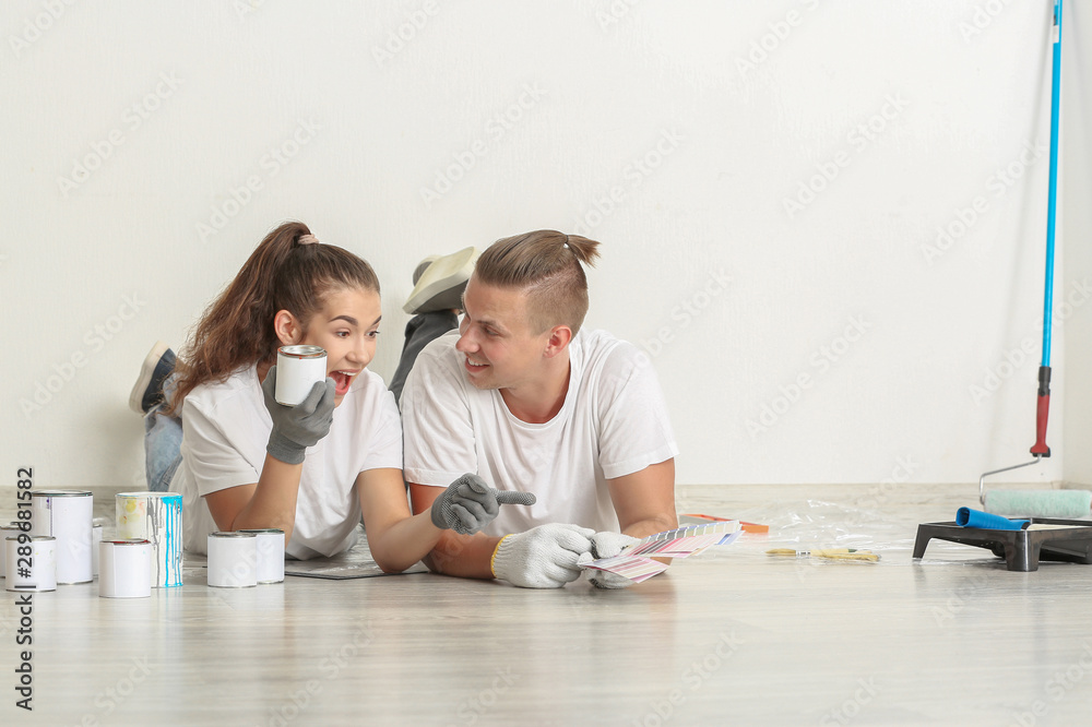 Happy young couple choosing color of paint for walls in their new house