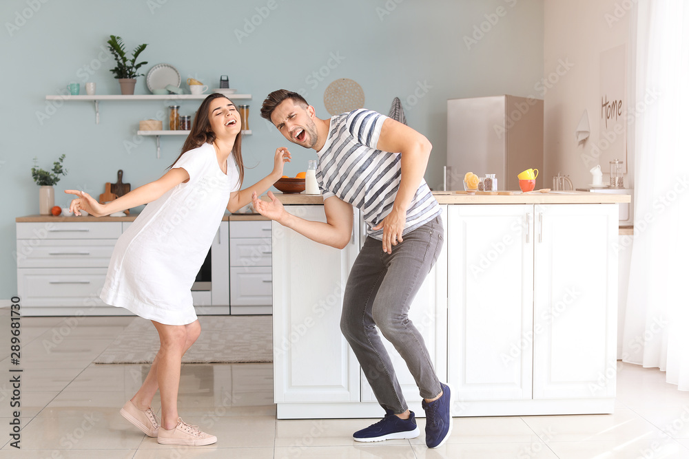 Happy young couple dancing in kitchen