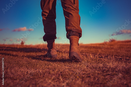 hiking and camping. travel adventure. future. military shoes. male feet in green boots. hynter searching for victim in grass field. going to success. freedom. soldier uniform. step up. walking. legs