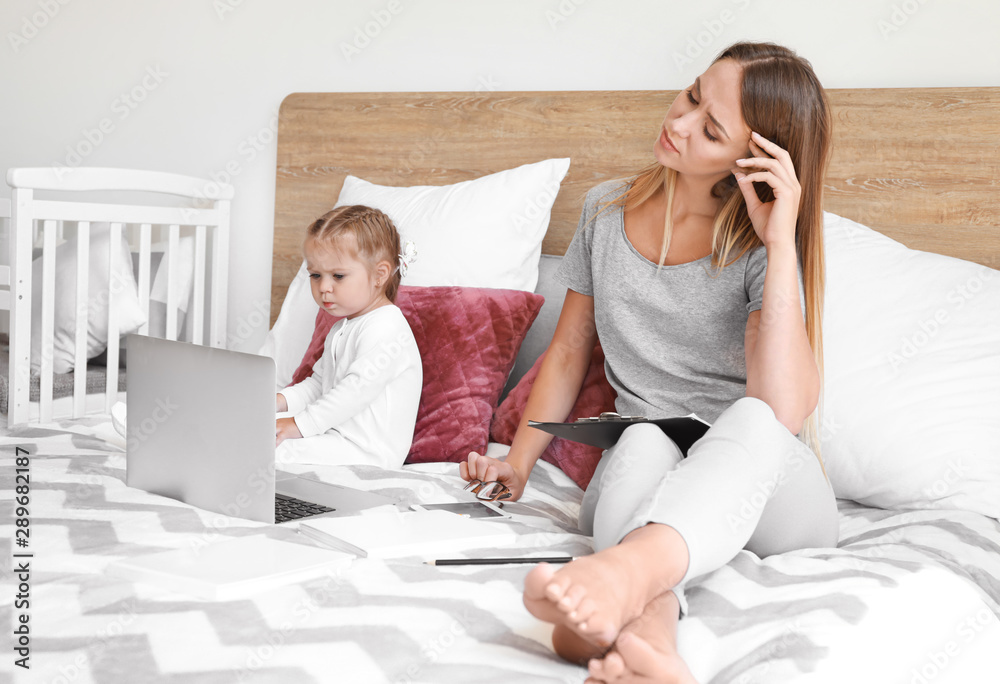 Tired mother with her daughter working in bedroom at home Tired mother with her daughter working in bedroom at home