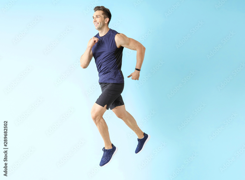 Fototapeta premium Running sporty man on color background